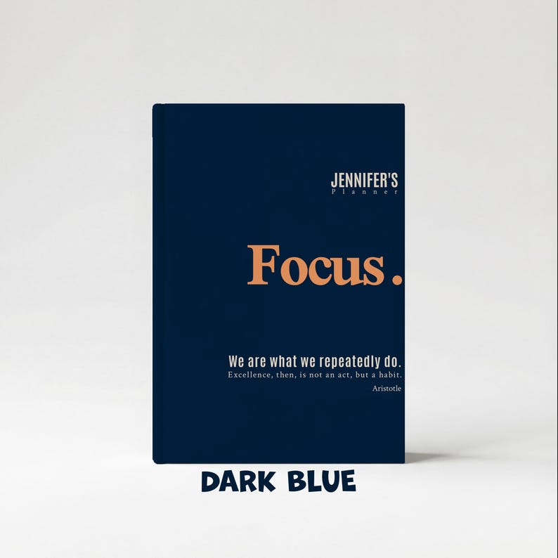 May include: A dark blue planner with the text "JENNIFER'S Planner" at the top. The word "Focus" is in large orange letters. Below, it reads "We are what we repeatedly do. Excellence, then, is not an act, but a habit. Aristotle." The bottom reads "DARK BLUE."