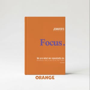 May include: An orange planner with the text "Focus" in blue. The planner also includes the text "JENNIFER'S planner", a quote by Aristotle, and the word "ORANGE".