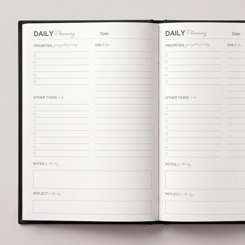 May include: Open black notebook with the words "DAILY Planning" at the top of each page. The pages are lined with sections for priorities, tasks, notes, and reflection. The notebook is open, displaying two facing pages.