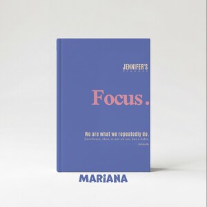 May include: A blue planner with the text "JENNIFER'S PLANNER" at the top. The word "Focus" is in large pink letters. Below, it reads "We are what we repeatedly do." and "MARIANA" at the bottom.