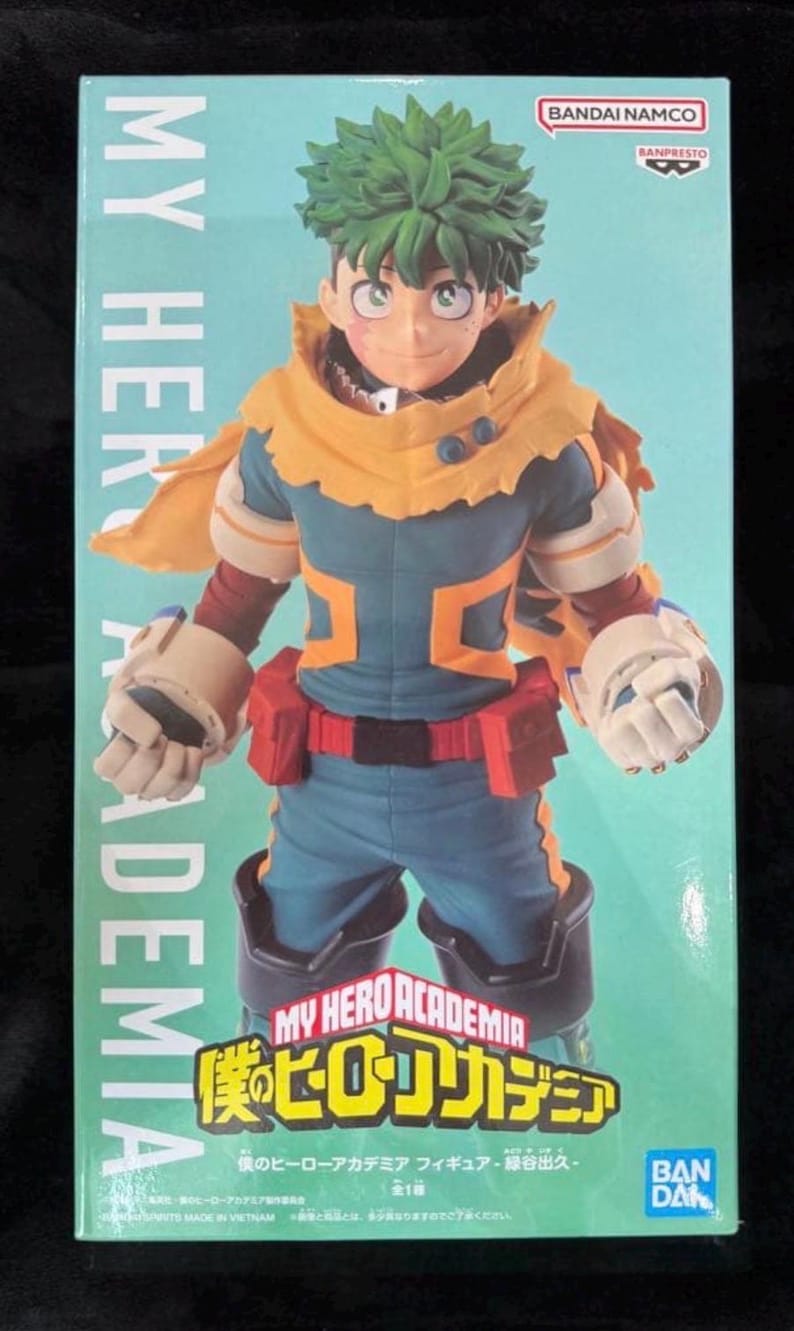 May include: A boxed action figure of a character from "My Hero Academia." The figure is of a male character with green hair, wearing a blue and orange costume. The box has the show's logo and the Bandai Namco and Banpresto logos.