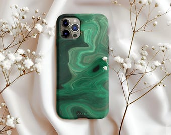 May include: A green iPhone case with a malachite pattern. The case has a glossy finish and features the brand name "ZARRI" at the bottom. The case is surrounded by white flowers and rests on a white satin surface.