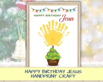 May include: A framed print featuring the text HAPPY BIRTHDAY Jesus with a string of colorful Christmas lights above. A yellow handprint sits above a green cupcake with a lit candle and the year 2026 printed on the brown cupcake liner.