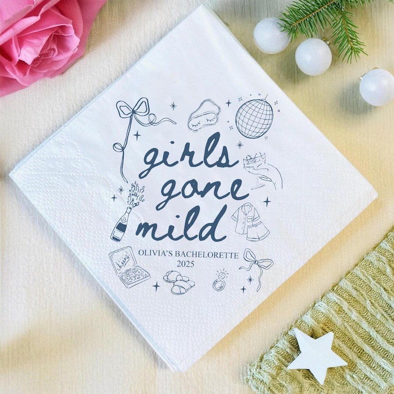May include: White square paper napkin with the phrase "girls gone mild" in dark blue script, along with illustrations of a disco ball, champagne bottle, and other party-themed graphics. The text "Olivia's Bachelorette 2025" is also printed on the napkin.