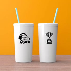 May include: Two white tumblers with blue straws. One tumbler features a black cartoon car graphic, and the other has a black trophy graphic. The background is a solid orange color.