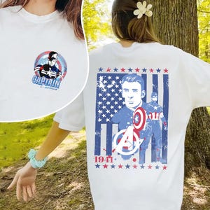 May include: White t-shirt featuring Captain America graphics. The front has a circular design with the text "Captain America." The back displays a patriotic design with Captain America, the Avengers logo, and the year 1941.