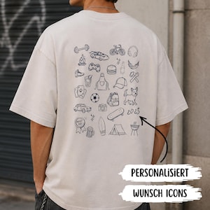 Könnte beinhalten: Ein beiges T-Shirt mit kurzen Ärmeln und einer Ansammlung schwarzer Strichzeichnungen auf der Rückseite, darunter eine Hantel, ein Auto, ein Fahrrad, ein Burger, ein Hund, ein Skateboard und der Text 2023. Das Design zeigt diverse Hobbysymbole.