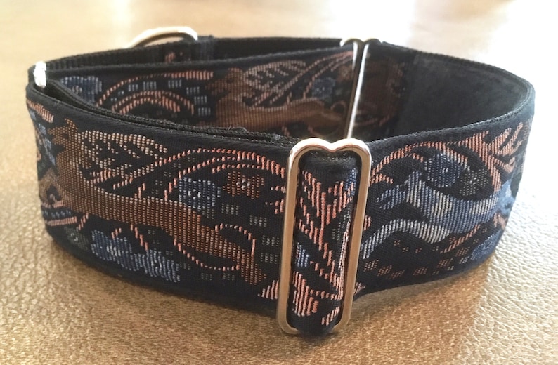 Puede incluir: Un collar negro para perros con un patr&oacute;n decorativo tejido en tonos marr&oacute;n, azul y rosa. El collar presenta herrajes met&aacute;licos plateados. El patr&oacute;n tiene un dise&ntilde;o floral y geom&eacute;trico.