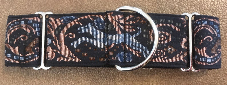 Puede incluir: Un collar negro para perros con un patr&oacute;n decorativo que presenta un caballo corriendo y elementos florales en tonos azules, beige y blanco. El collar tiene un anillo en D de metal plateado y herrajes ajustables.