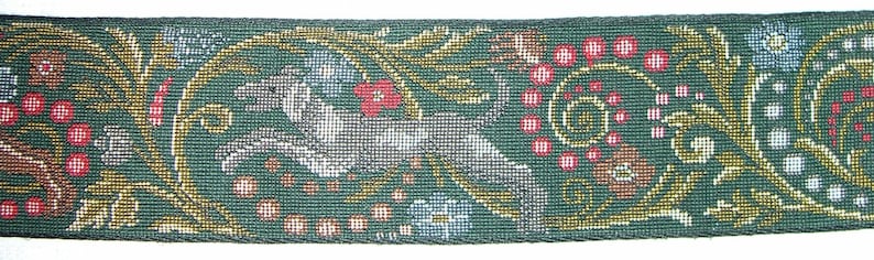 Puede incluir: Cinta tejida verde con un patr&oacute;n repetitivo de un animal blanco, bayas rojas y elementos florales. El dise&ntilde;o incluye detalles dorados y marrones, creando una apariencia detallada y texturizada. Adecuada para manualidades y proyectos decorativos.