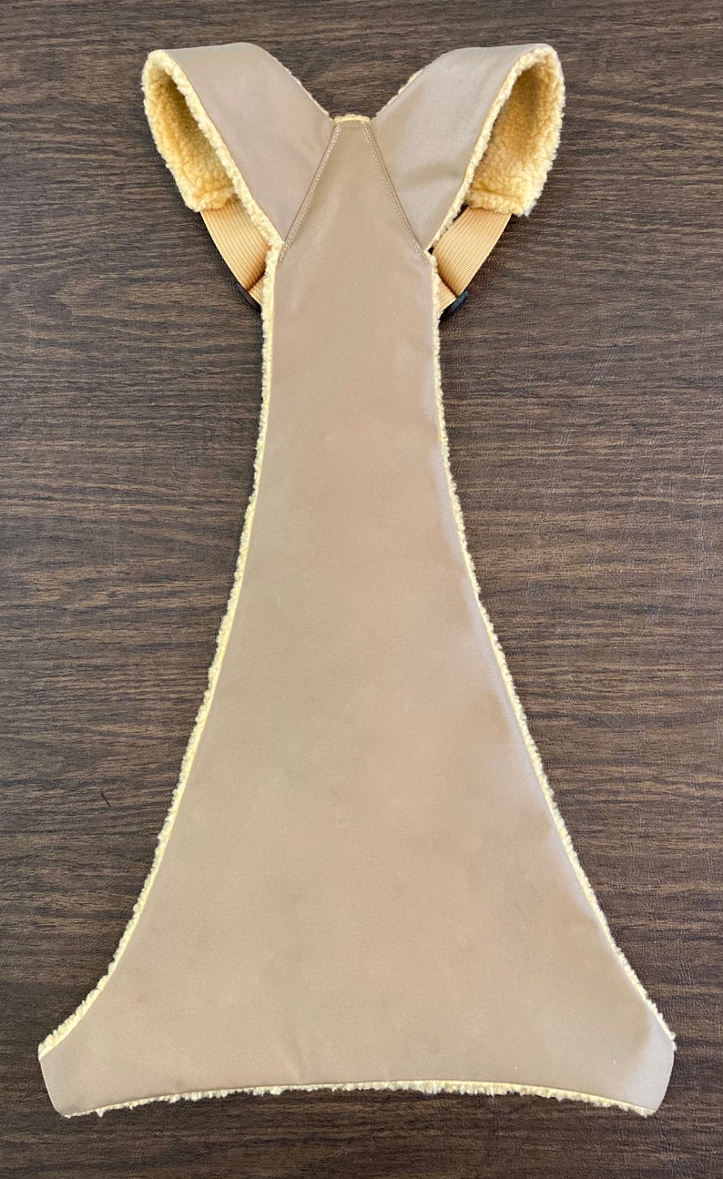 Op de afbeelding: Een beige gewatteerd vest met een nep bont randje rond de randen en banden. Het vest heeft een Y-vormige rug.