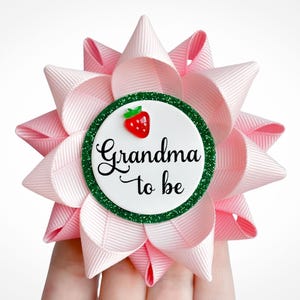 Sweet Little One theme baby shower pin made of pink ribbon with green accent and red strawberry. Custom text: Grandma to be