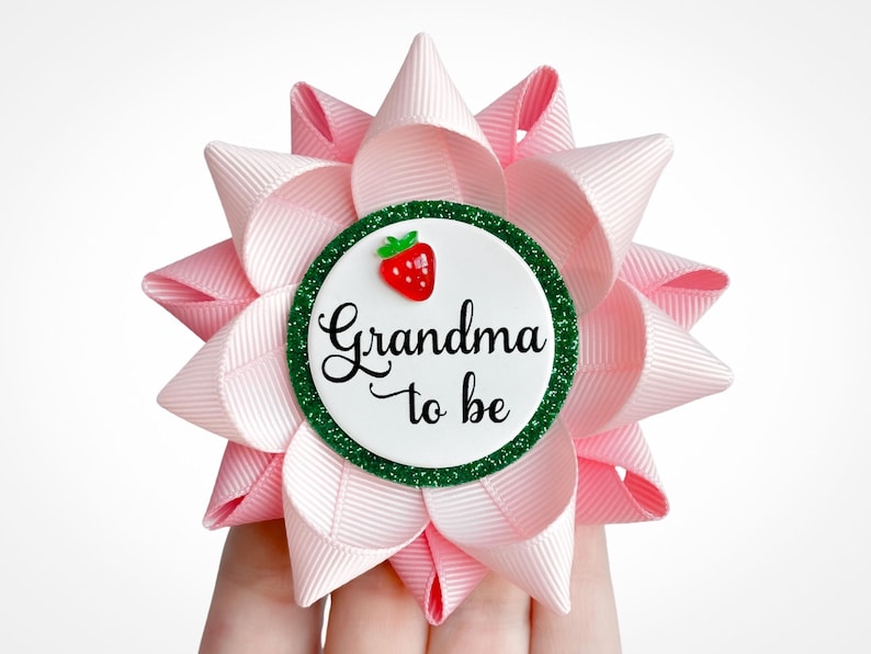 Sweet Little One theme baby shower pin made of pink ribbon with green accent and red strawberry. Custom text: Grandma to be