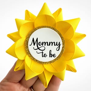 Baby shower pin made of yellow grosgrain ribbon with gold accent and custom text: Mommy to be