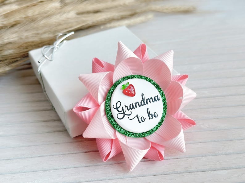 May include: Pink and green bow with a white circle that says "Grandma to be" and a red strawberry graphic.