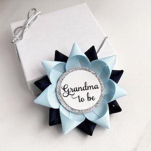 May include: A blue and navy blue bow with a silver glitter circle that says "Grandma to be" in black script.