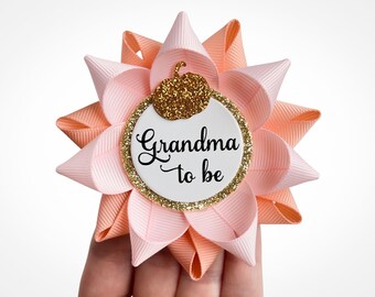 May include: Peach and pink flower-shaped pin with a gold glitter pumpkin and the text "Grandma to be".