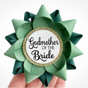 May include: Green and teal satin ribbon bow with a gold glitter circle that says "Godmother of the Bride".