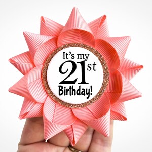 May include: A pink and gold 21st birthday rosette with the text "It's my 21st Birthday!"