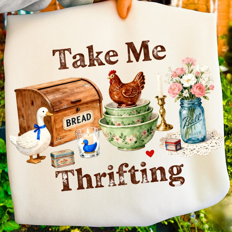 May include: A white tote bag with the words "Take Me Thrifting" in brown. The bag features illustrations of a bread box, duck, bowls, chicken, candle, flowers in a jar, and other vintage items.