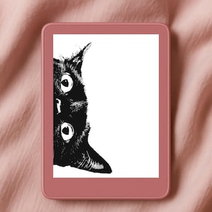 May include: A digital e-reader with a black and white illustration of a black cat's face. The cat's eyes are wide and round. The e-reader has a rose-colored frame and is set against a pink fabric background.
