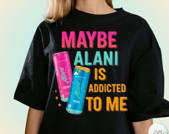 May include: Black t-shirt with the text "MAYBE ALANI IS ADDICTED TO ME" in pink, teal, and orange. Two Alani Nu energy drink cans are featured, one pink and one blue, with the word "ENERGY" on them.