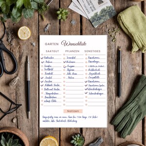 Puede incluir: Una lista de deseos de jard&iacute;n en alem&aacute;n sobre papel blanco, con bol&iacute;grafos, tijeras y guantes de jardiner&iacute;a sobre una superficie de madera. La lista est&aacute; dividida en secciones para semillas, plantas y otros art&iacute;culos.