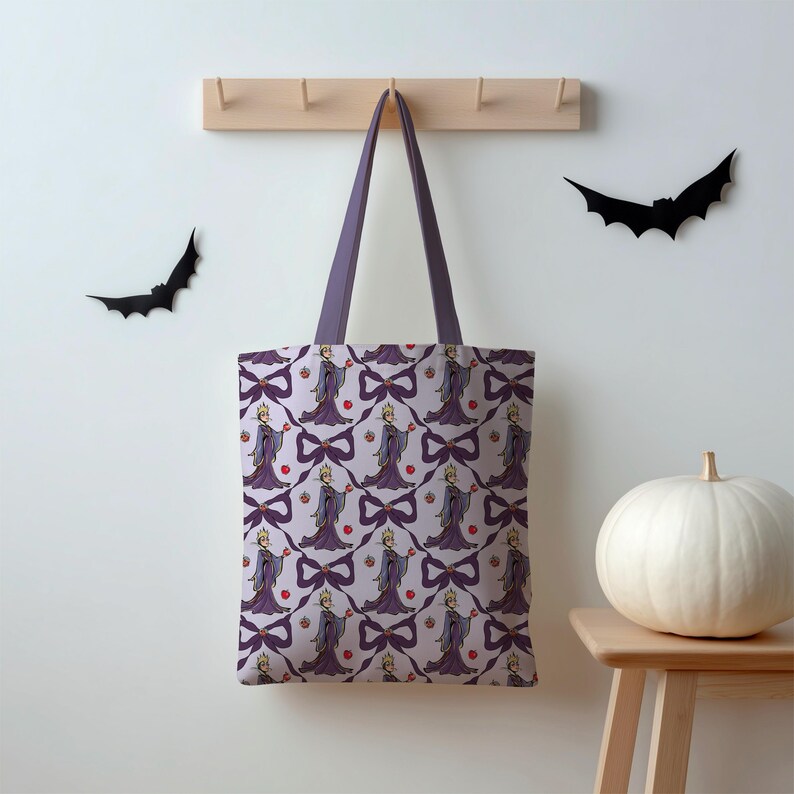 May include: A tote bag featuring a repeating pattern of a cartoon character in a purple dress, holding an apple, and a purple bow. The bag has purple handles. The background is a light purple colour. Two black bat silhouettes are on the wall.