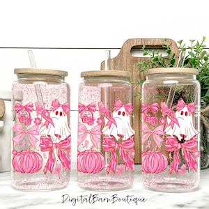 May include: Three glass tumblers with wooden lids and straws. Each tumbler features a pink and gold design with a ghost, bows, pumpkins, and pink ribbons. The text "Digital Barn Boutique" is at the bottom.
