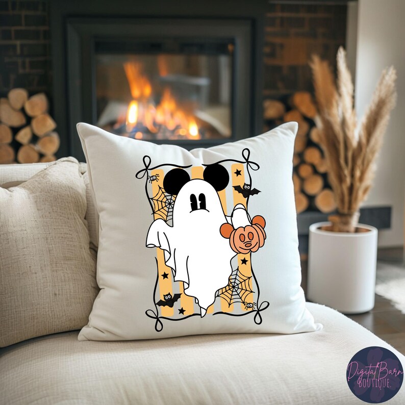 May include: White Halloween-themed pillow featuring a cartoon ghost with Mickey Mouse ears holding a pumpkin. The design includes bats, spiderwebs, and stars on a yellow and white striped background, framed with black decorative elements.