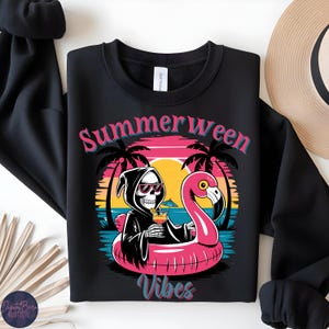 May include: Black crewneck sweatshirt with a graphic featuring a Grim Reaper in sunglasses, holding a cocktail while floating on a pink flamingo pool float. The text "Summerween Vibes" is displayed in pink and teal.