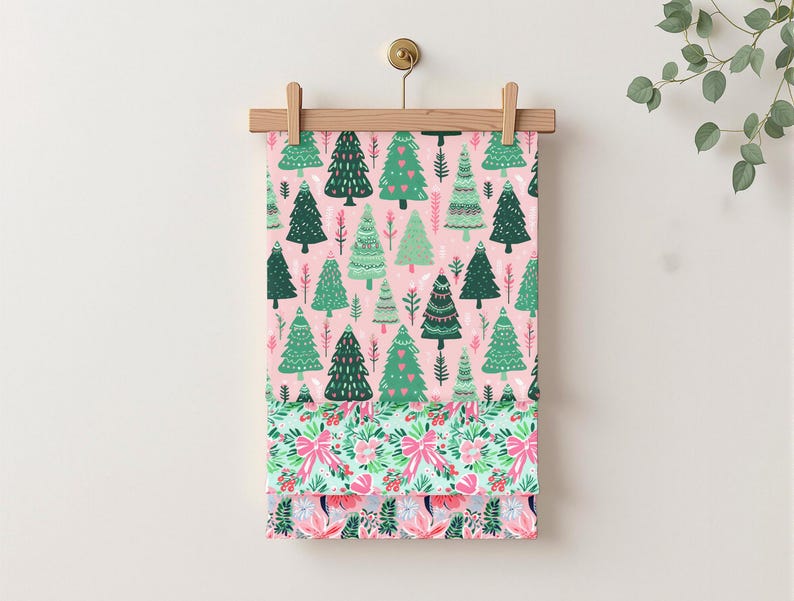 May include: A fabric panel with a repeating pattern of green Christmas trees on a pink backdrop. The lower section shows a floral and bow design in pink and green. The fabric is suspended from a wooden hanger.