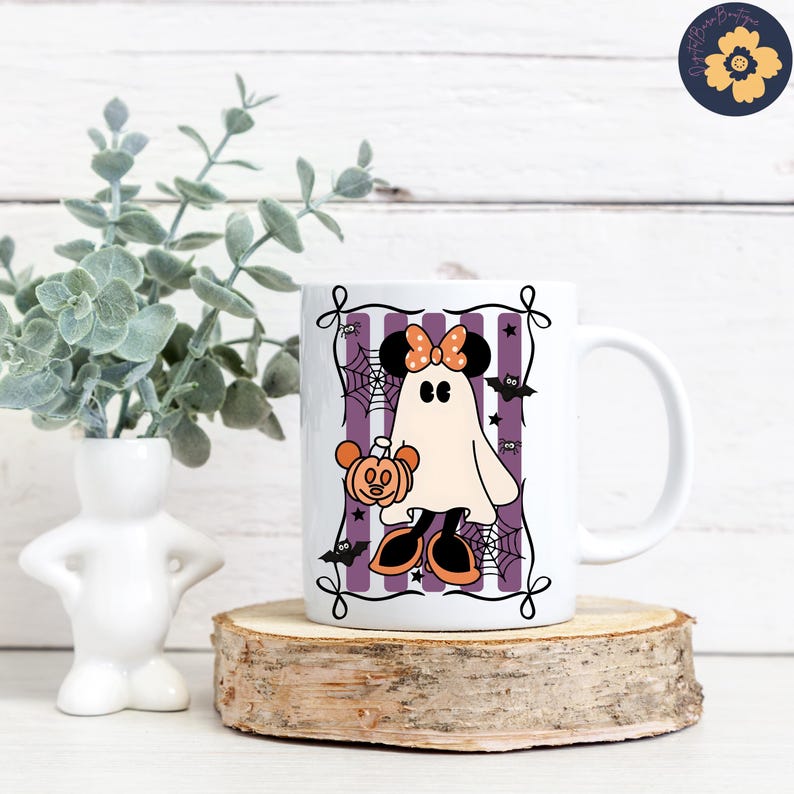 May include: White ceramic mug featuring a Halloween-themed design. The design includes a ghost character with a bow, holding a pumpkin, set against a purple and white striped background with spiderwebs and bats. The mug is displayed on a wooden slice.