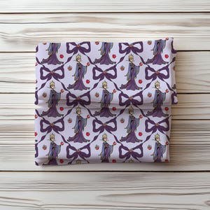 May include: Folded fabric with a repeating pattern of a queen holding an apple, bows, and apples. The queen wears a purple gown and crown. The bows are dark purple, and the apples are red.