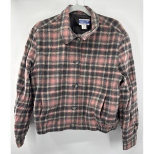 May include: A pink, gray, and black plaid jacket with a button-up front and two front pockets. The jacket has a rounded collar and a black lining. The brand name "Pendleton" is visible on a tag.