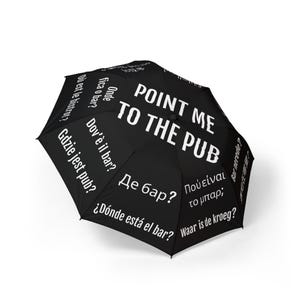 May include: Black umbrella with the text "POINT ME TO THE PUB" in large white letters. Additional phrases in various languages, including "Where is the bar?" and "Where is the pub?" are printed on the umbrella.