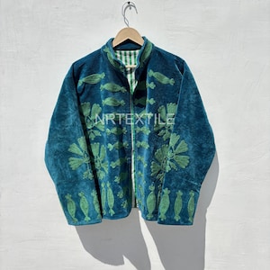 Könnte beinhalten: Türkisblaue Samtjacke mit grün gestickten Blumen- und Blättermustern. Die Jacke hat einen Stehkragen und ein gestreiftes grün-weißes Futter. Der Text "NRTEXTILE" ist auf der Vorderseite gestickt.