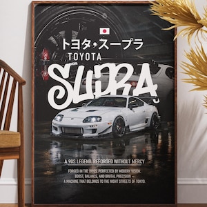 Puede incluir: Un póster enmarcado con un coche deportivo Toyota Supra blanco. El póster tiene texto japonés y la palabra "SUPRA" en letras blancas grandes. El fondo es oscuro con una superficie mojada, y el póster está en un marco de madera.