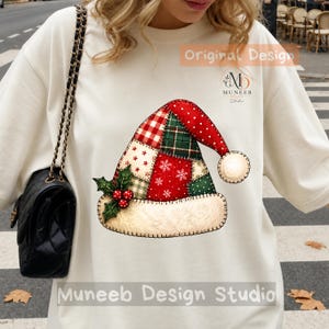 May include: A cream-colored crewneck sweatshirt featuring a graphic of a patchwork Santa hat. The hat design includes red and green plaid, polka dots, and snowflake patterns with a holly sprig. Text reads Original Design and Muneeb Design Studio.