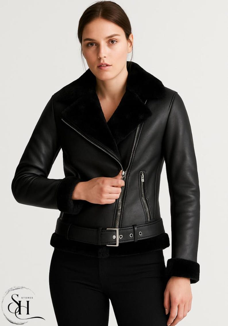 May include: Black faux leather jacket with a faux fur collar and cuffs. The jacket features a silver zipper closure, a belt with a silver buckle, and a tailored fit. A stylish outerwear piece.