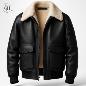 Könnte beinhalten: Schwarze Lederjacke mit cremefarbenem Shearling-Kragen und -Futter. Die Jacke hat zwei Vordertaschen, zwei Brusttaschen sowie einen gerippten Saum und Bündchen. Ein Reißverschluss verläuft vorne.