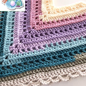 May include: A handmade crochet shawl in a square shape, featuring a gradient of colors from teal to cream. The design includes openwork and a scalloped edge. The colors transition from teal to blue, purple, pink, and cream. The logo "The Barry Pearl" is in the upper left corner.