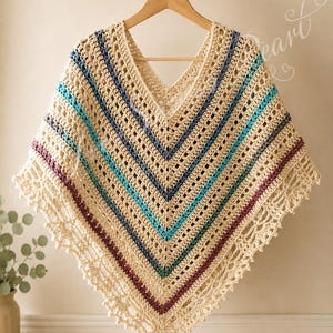 May include: A beige crochet poncho featuring a V-neckline and a V-shaped pattern of horizontal stripes in shades of dark blue, turquoise, and maroon. The garment is finished with a decorative, intricate lace-like border along the bottom edge.