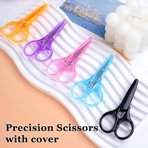 May include: An assortment of colorful precision scissors with covers. The scissors come in yellow, purple, pink, blue, and black. The text "Precision Scissors with cover" is displayed at the bottom of the image.