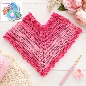 May include: A V-shaped crochet poncho featuring an ombre gradient of pink and magenta yarn. The garment has a textured stitch pattern with a scalloped edge along the perimeter. A pink crochet hook and a ball of light pink yarn are visible nearby.