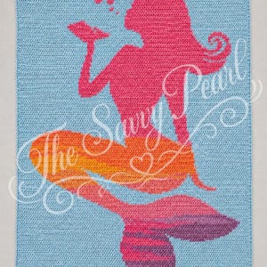 May include: A rectangular crochet blanket featuring a light blue background with a central graphic of a mermaid in pink, orange, and purple tones. The mermaid is depicted blowing bubbles, with the text The Savy Pearl overlaid in white script.