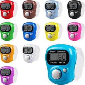 May include: A collection of digital tally counters in various colors, including red, brown, blue, black, green, yellow, pink, orange, white, and purple. Each counter displays "180" and has a reset button.