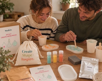 May include: A DIY resin craft kit featuring a beige drawstring bag with the text Create Shape: Inspire, a cardboard box labeled Stukits DIY KIT CREATE RESIN PIECES, resin powder packets, mixing cups, wooden stir sticks, and oval silicone molds.
