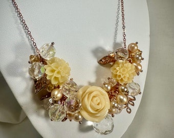 Fleurs en os sculpté, avec des accents de verre, de cristal, de perle d'eau douce et de métal doré rose