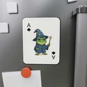 May include: A playing card magnet featuring a cartoon frog wizard. The frog wears a blue wizard hat with gold stars, a blue robe, and round glasses. The card is the Ace of Spades.